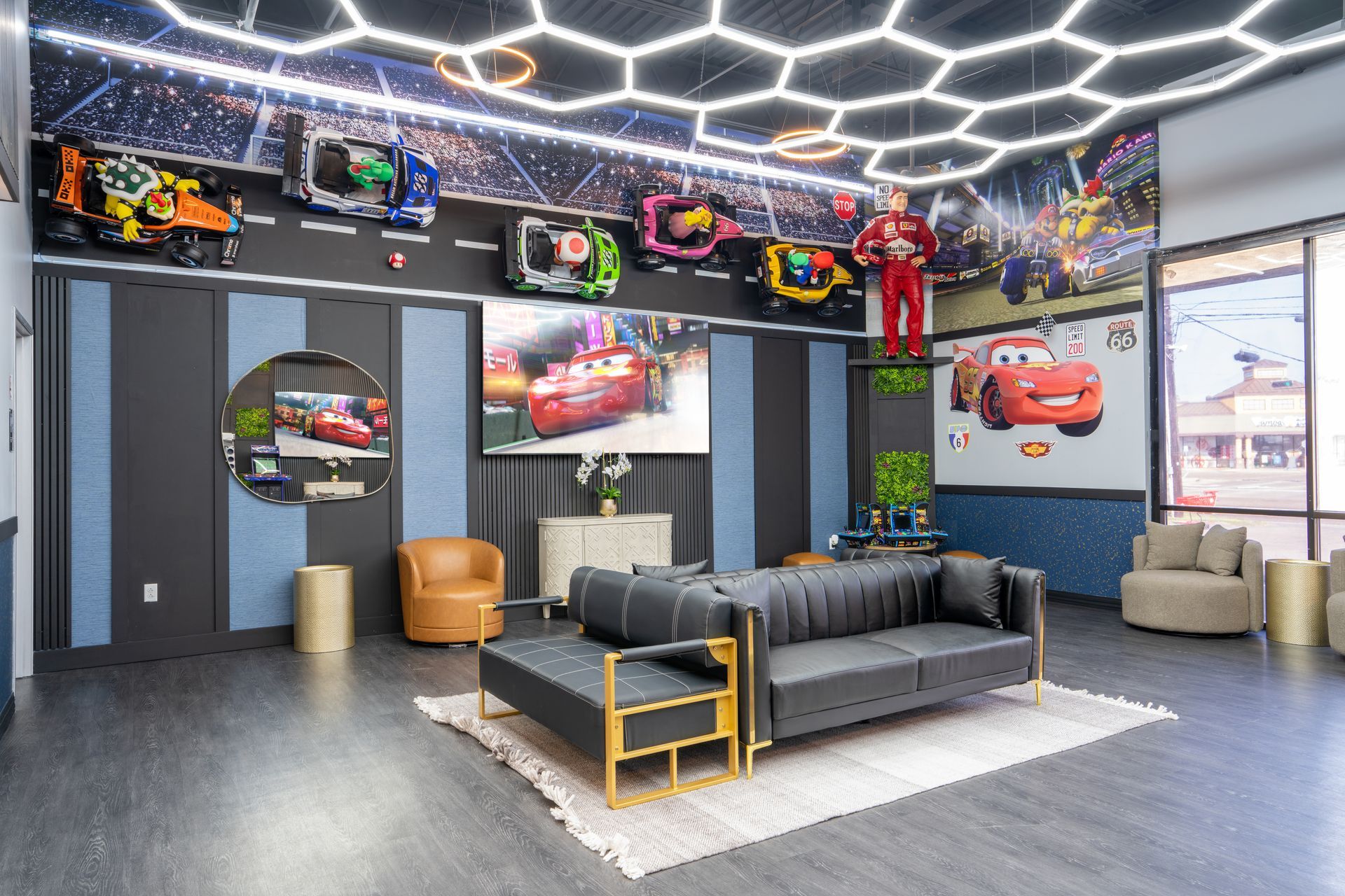 Modern lounge with racing-themed decor, cars on wall art, black sofa, and hexagonal ceiling lights