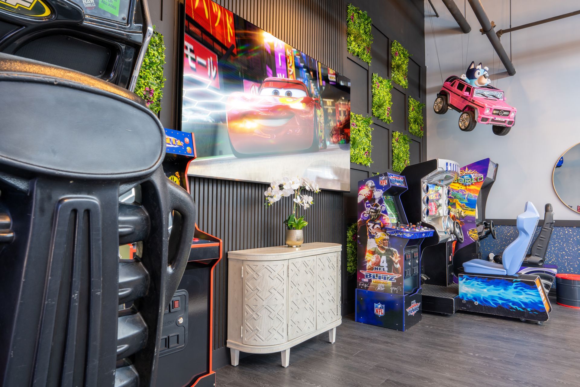 Colorful arcade room with racing game machines, wall screens, and neon decor