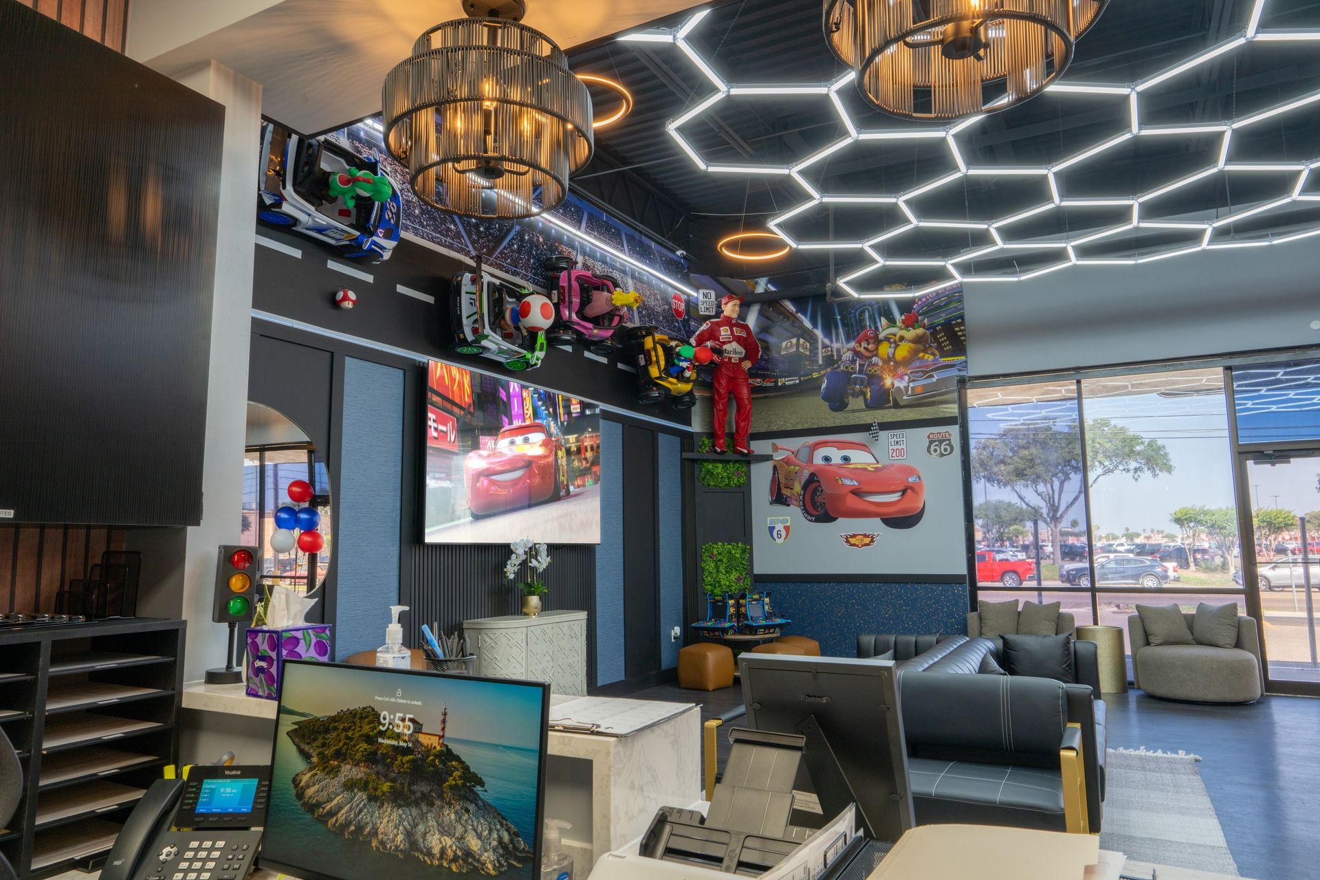 Modern lobby with neon hexagon ceiling lights, dark sofas, colorful wall art, and large windows