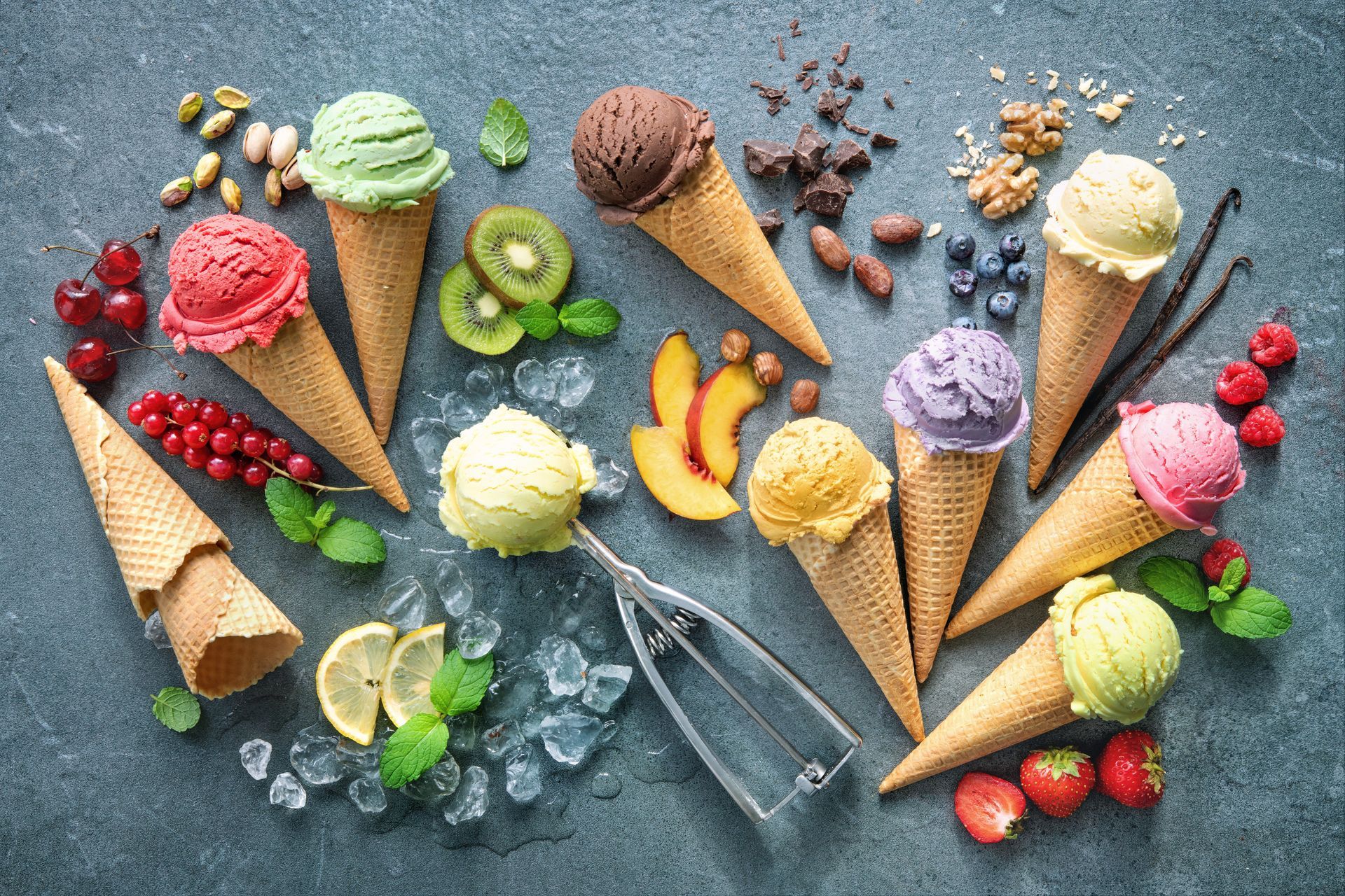 Assorted colorful ice cream cones and scoops with fruit on a blue background