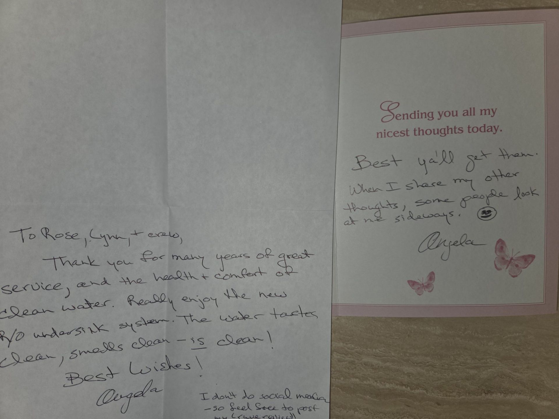 Open card with handwritten note on pink-lined paper beside a larger handwritten page.