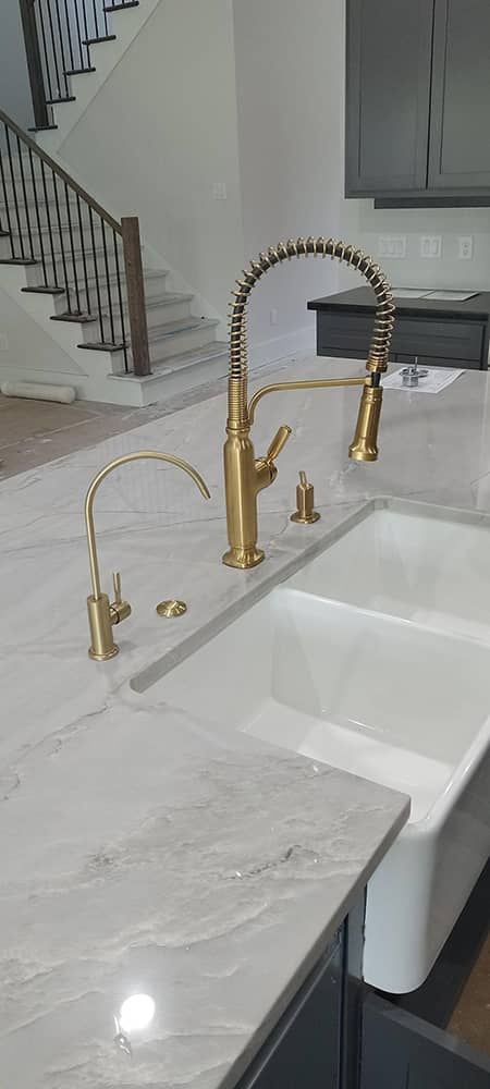 White kitchen sink with gold faucet and marble countertop with reverse osmosis for drinking and cooking water