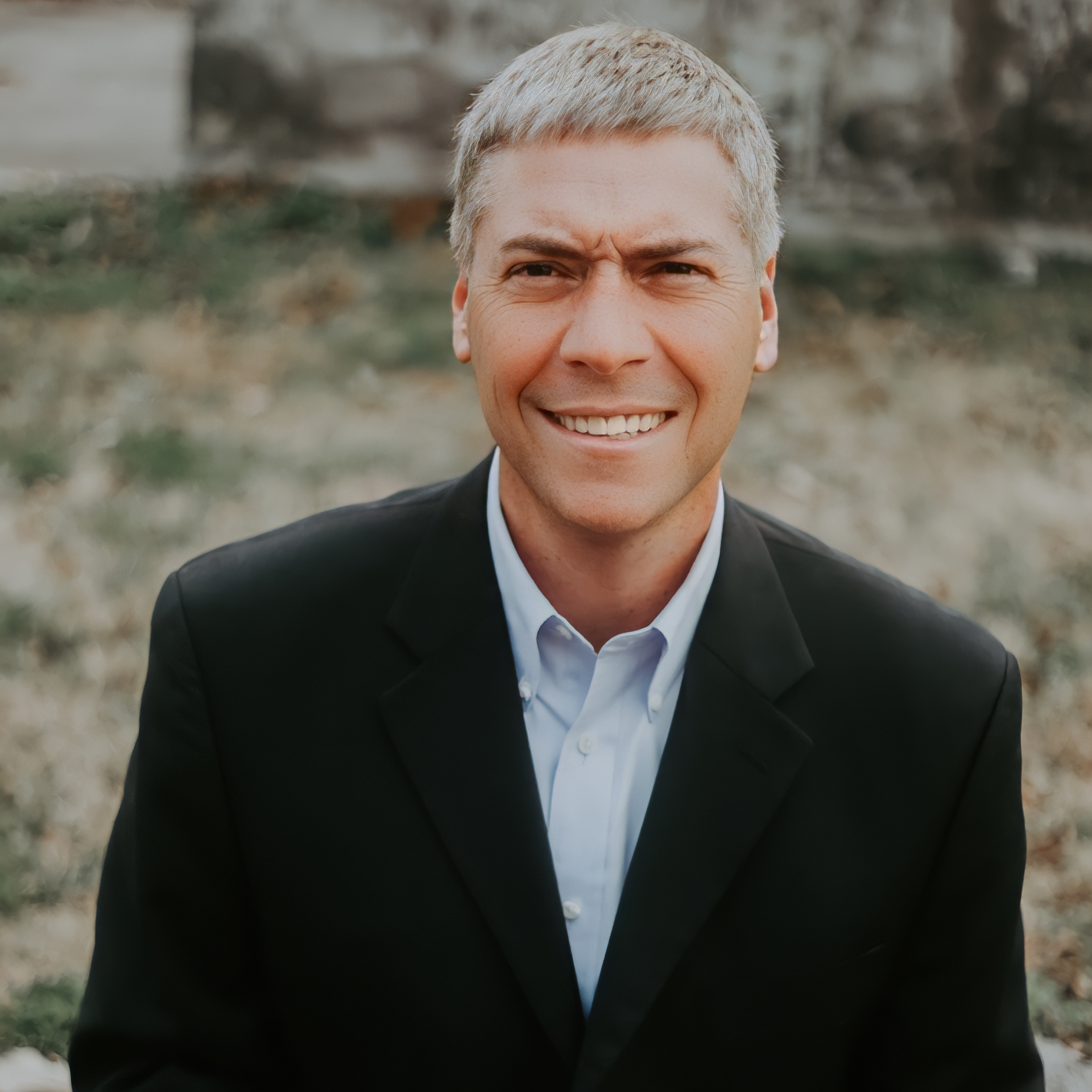 A man in a suit and blue shirt is smiling for the camera.