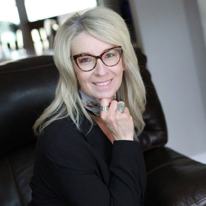 A woman wearing glasses and a scarf is sitting in a chair