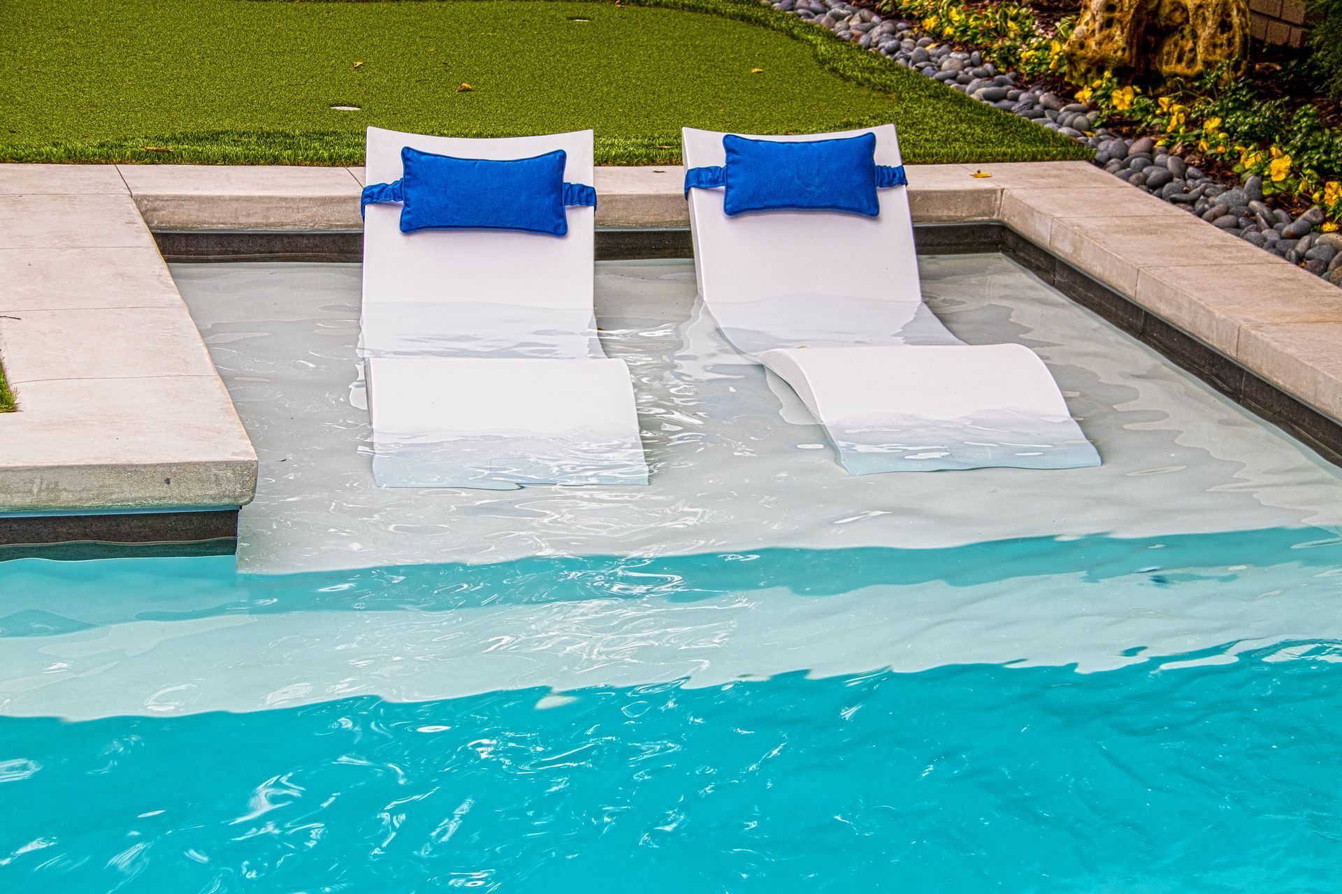 Pool with blue water and stainless steel ladder, surrounded by a paved deck and greenery with a scenic background. Pool with blue water and stainless steel ladder, surrounded by a paved deck and greenery with a scenic background.