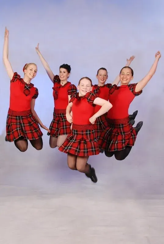 A Group Of Girls In Red Plaid Skirts Are Jumping In The Air — International Dance Affair In North Mackay, QLD