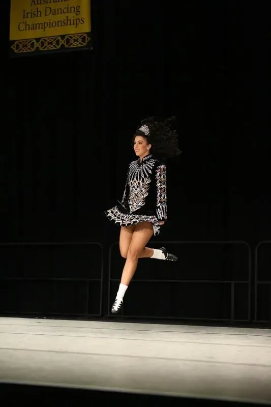 A Woman In A Black And White Dress Is Jumping In The Air On A Stage — International Dance Affair In North Mackay, QLD