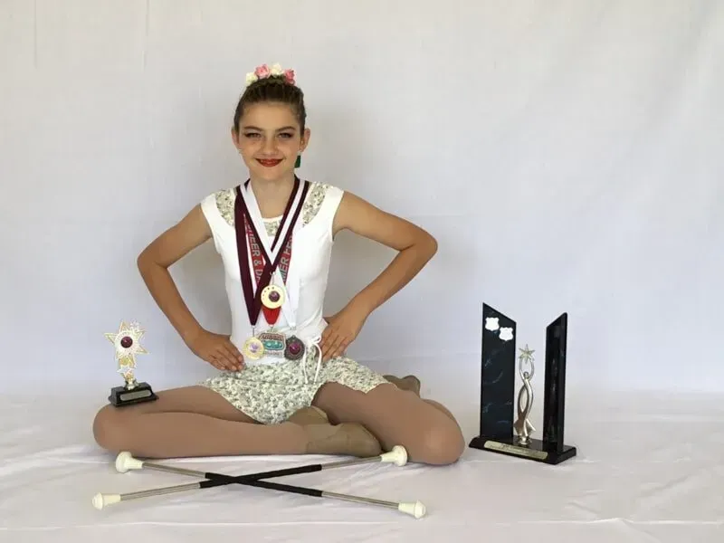 A Girls Is Sitting On The Floor With Medals And Trophies — International Dance Affair In North Mackay, QLD