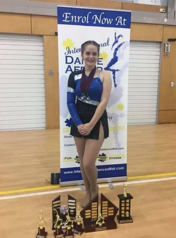 A Girl Is Standing In Front Of A Sign — International Dance Affair In North Mackay, QLD