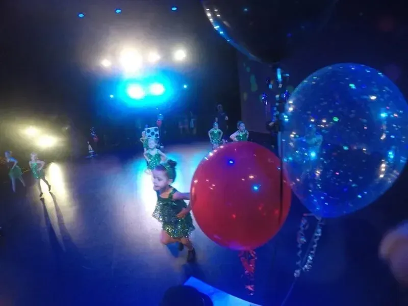 A Little Girl Is Holding A Red And Blue Balloon On A Stage — International Dance Affair In North Mackay, QLD