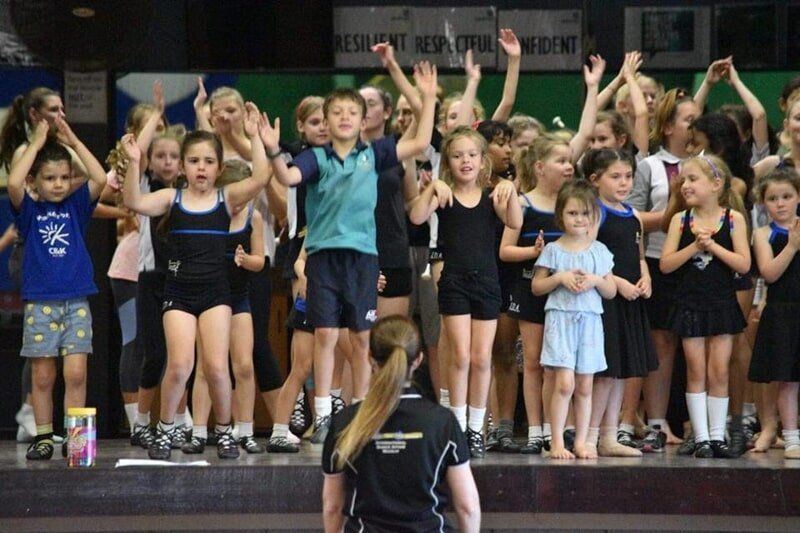 A Group Of Children Are Standing On A Stage With Their Hands In The Air — International Dance Affair In North Mackay, QLD