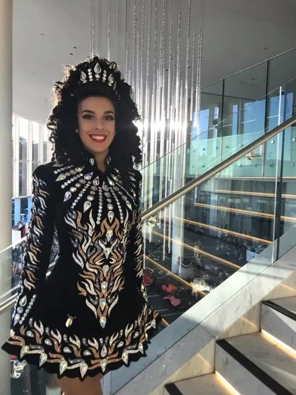 A Woman In A Black And Gold Dress Is Standing On A Set Of Stairs — International Dance Affair In North Mackay, QLD