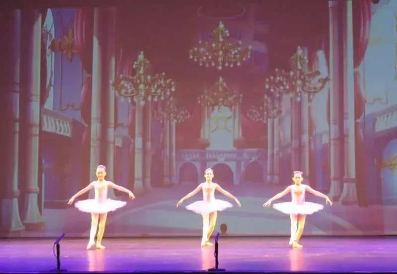Three Ballerinas Are Dancing On A Stage In Front Of A Large Screen — International Dance Affair In North Mackay, QLD