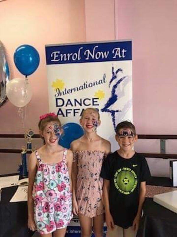 Three Children Are Standing In Front Of A Sign — International Dance Affair In North Mackay, QLD