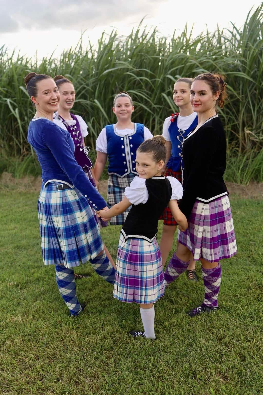 A Group Of Women In Kilts Are Standing In A Field Holding Hands — International Dance Affair In North Mackay, QLD