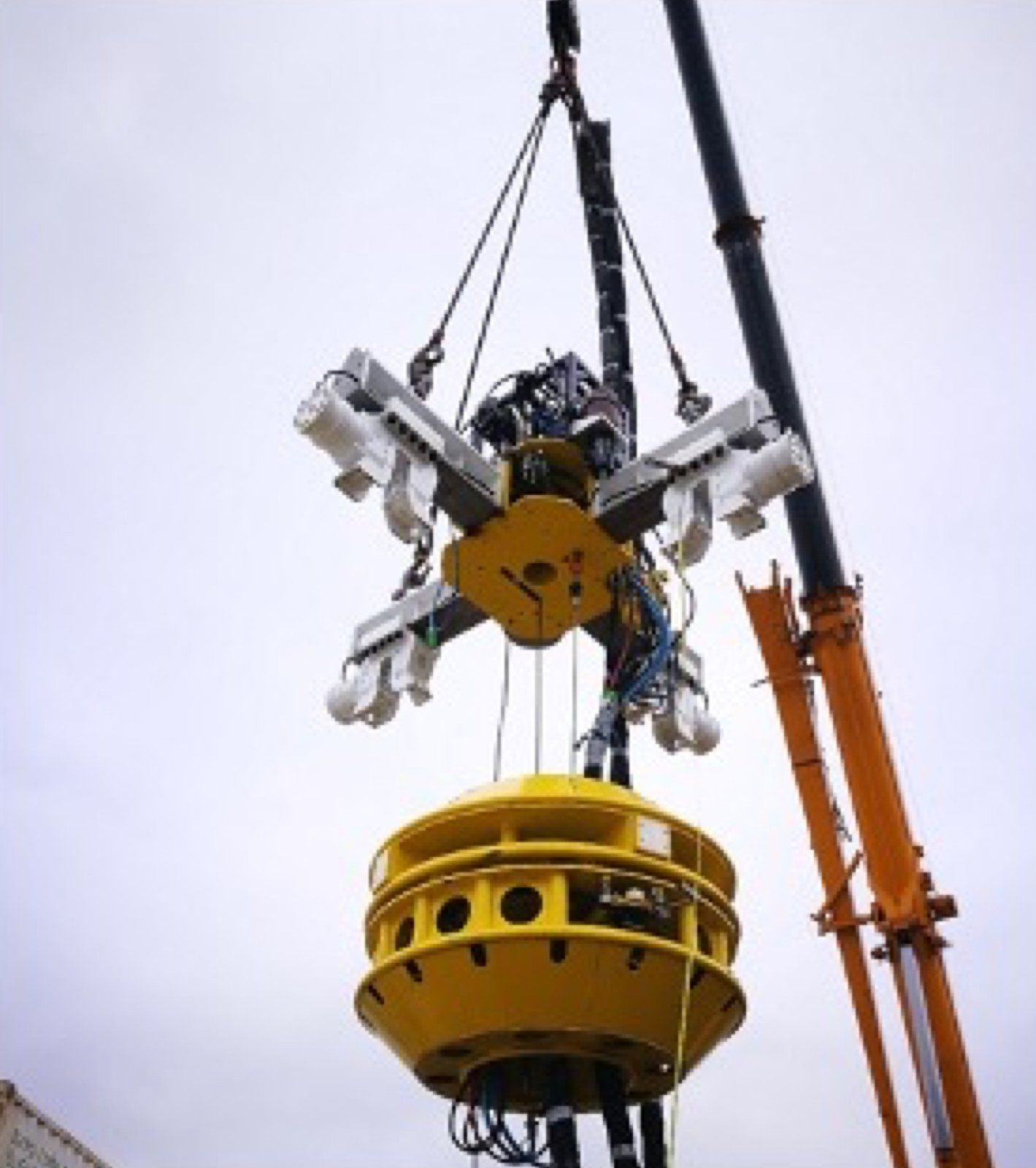 A cutting and lifting tool suspended by a crane.