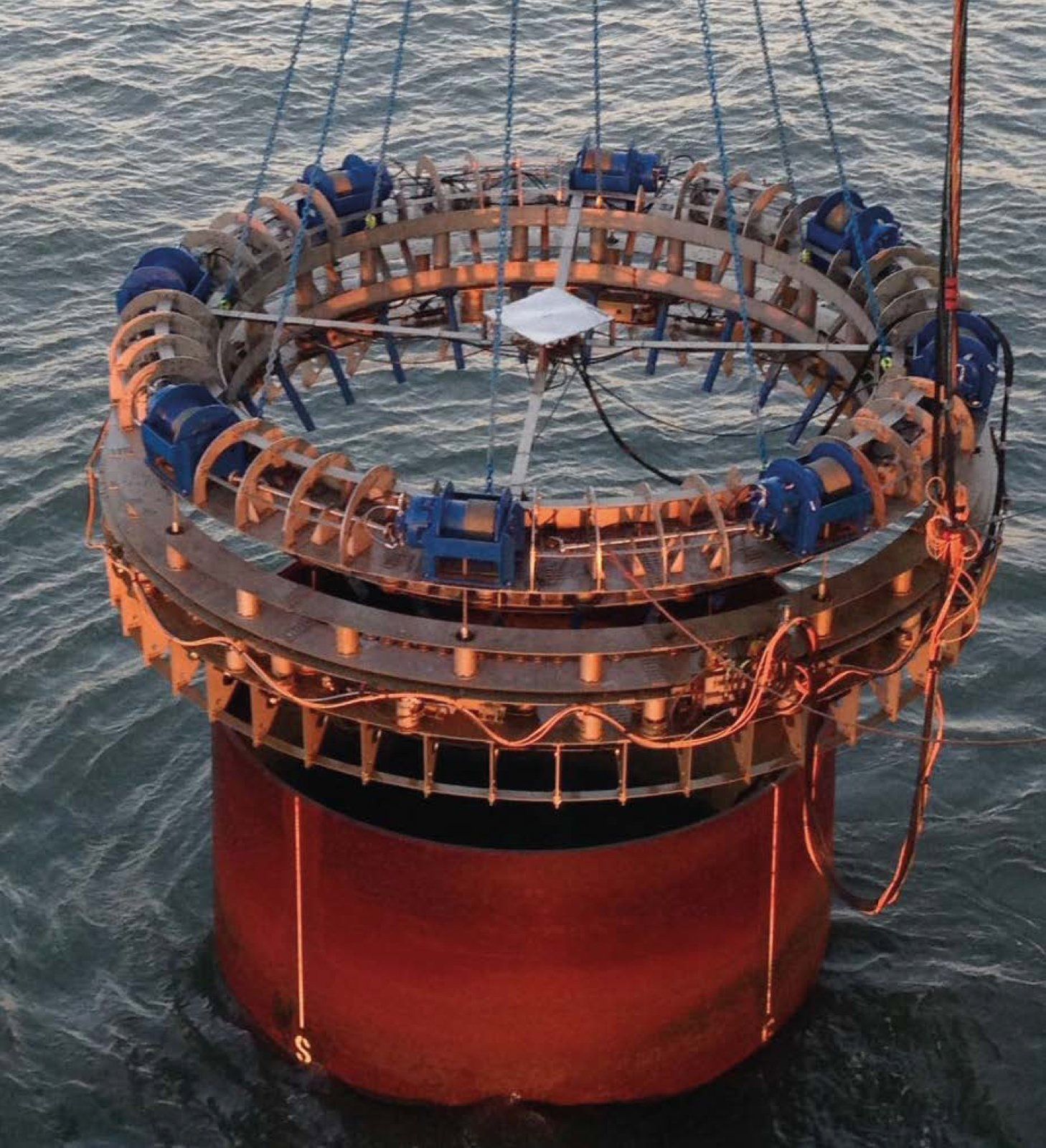 Circular wave energy converter floating in water, with blue and brown components.