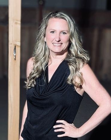 A woman in a black top is standing in front of a wooden post.