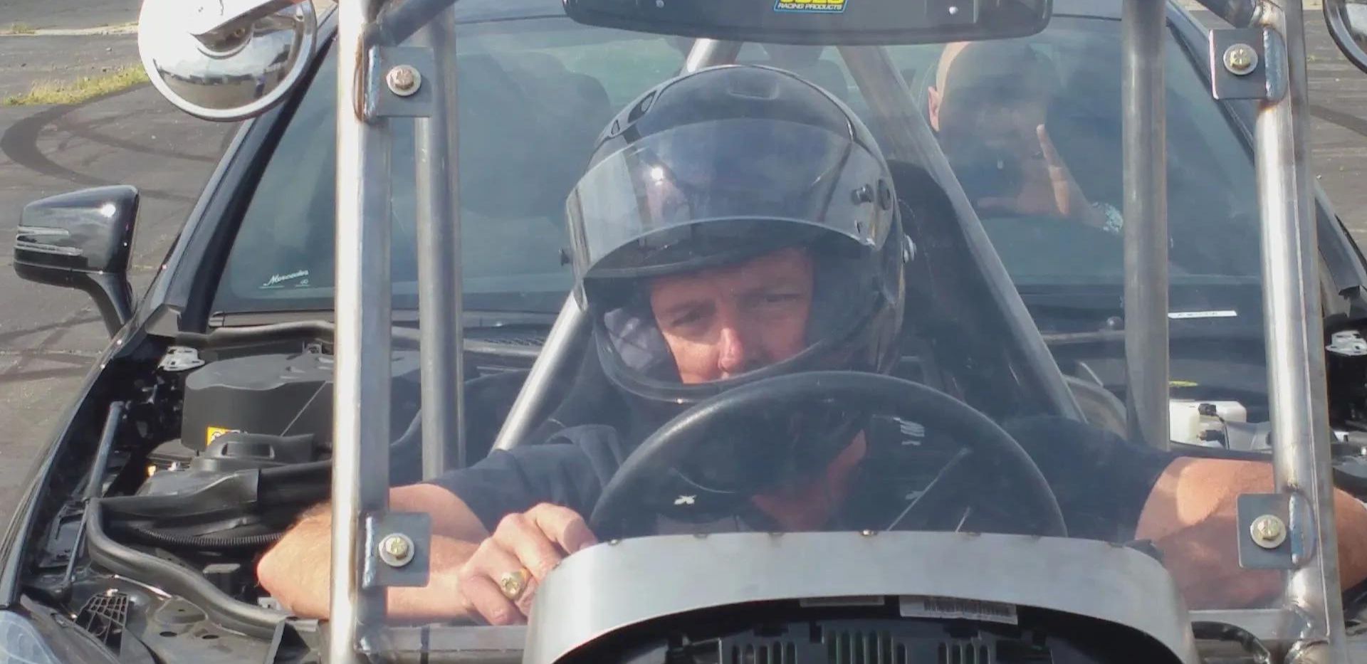 A man in a helmet drives a car, showcasing modern in-car filming techniques for enhanced safety and realism.
