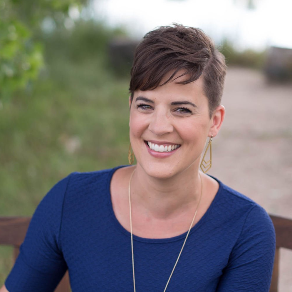 Portrait of white woman with short brown hair and blue top in an outdoor setting.