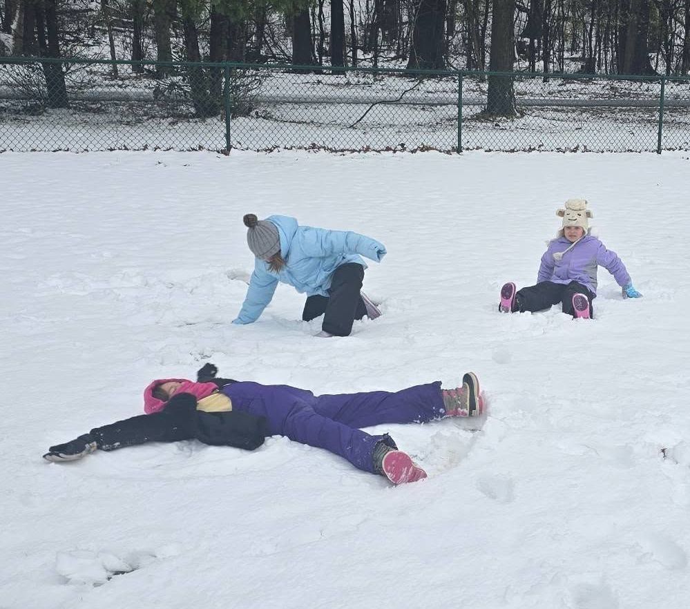 Children playing in the snow, making snow angels and enjoying the winter weather.