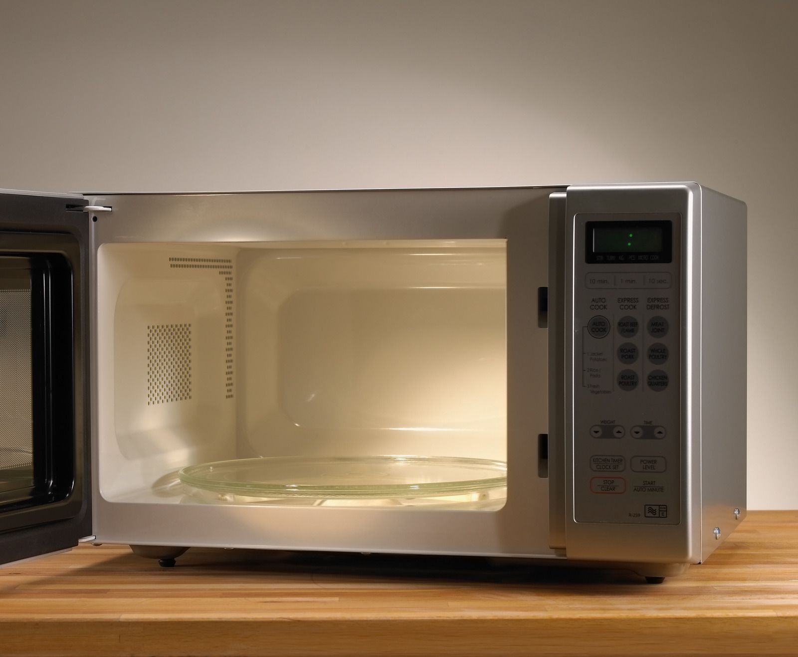 A man is fixing a microwave oven in a kitchen.