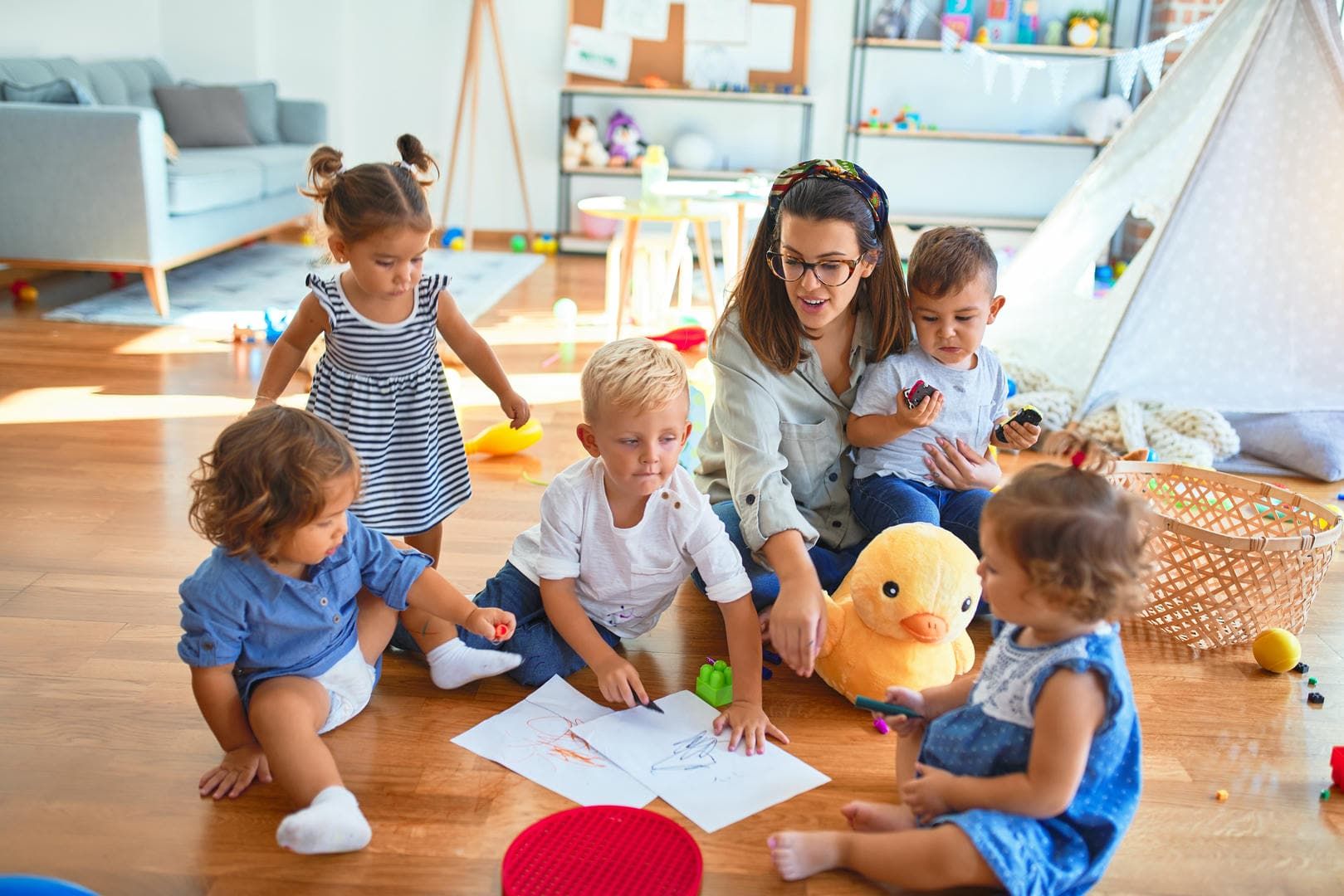 A woman is sitting on the floor with a group of children.