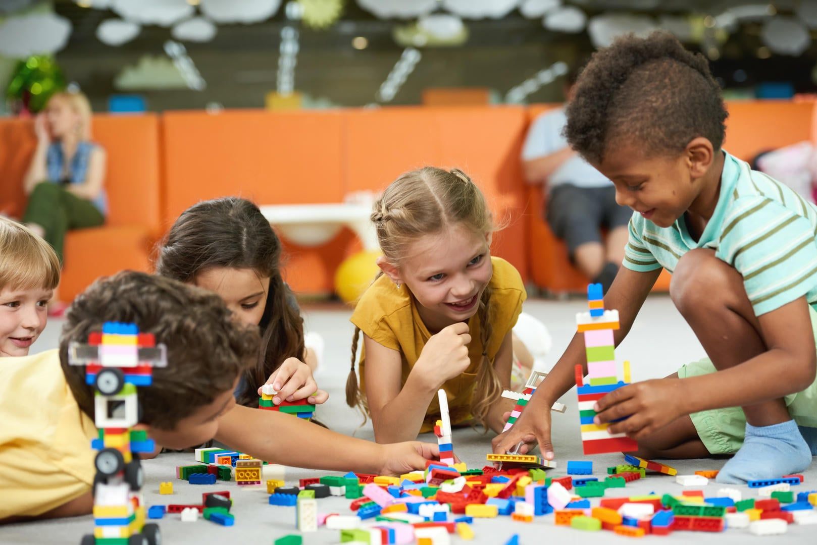 A group of children are playing with lego blocks on the floor.