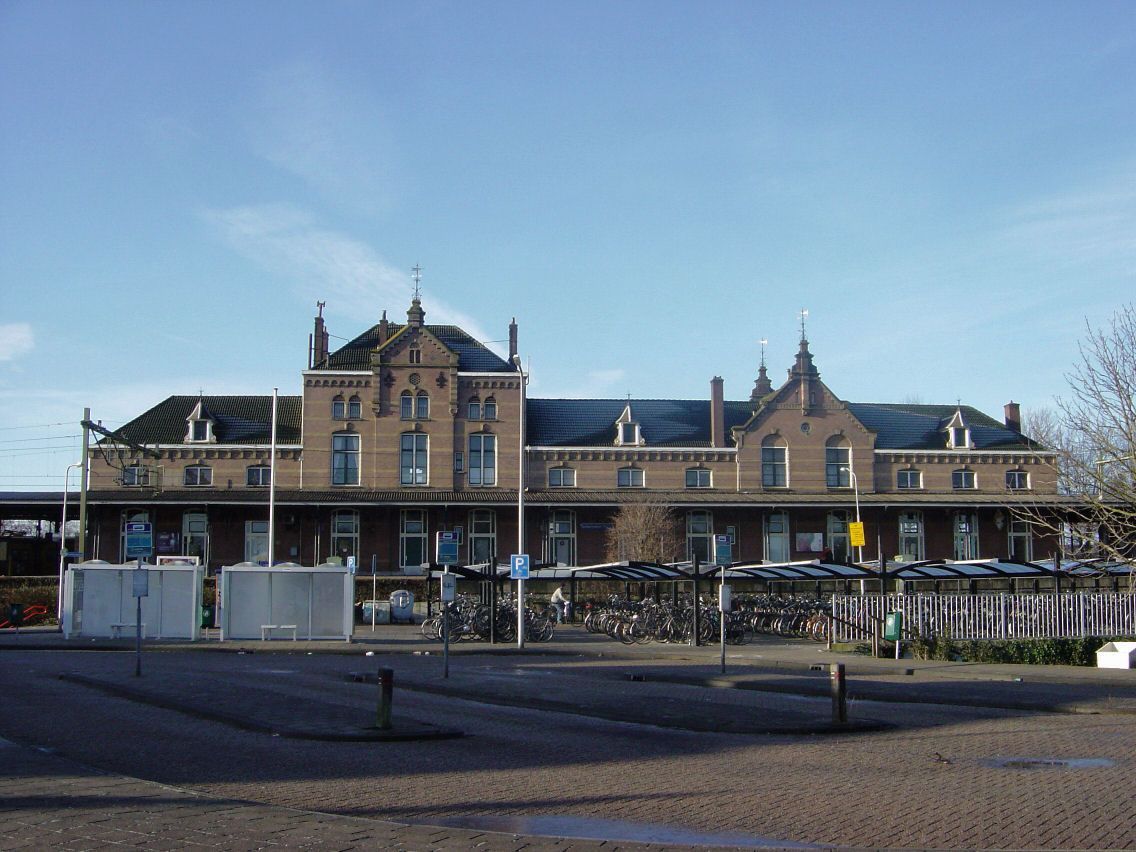 Een groot bakstenen gebouw met een parkeerplaats ervoor.