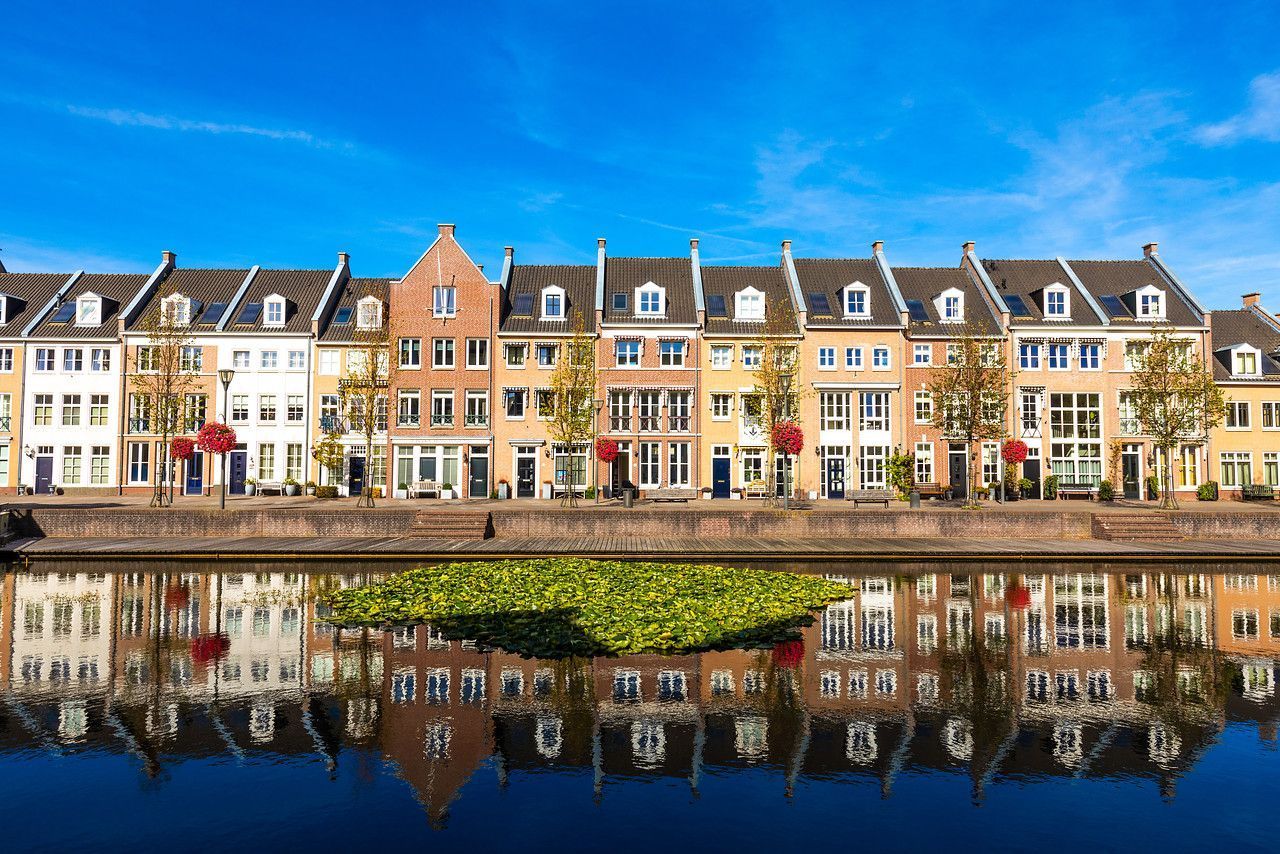 Een rij gebouwen wordt weerspiegeld in het water.