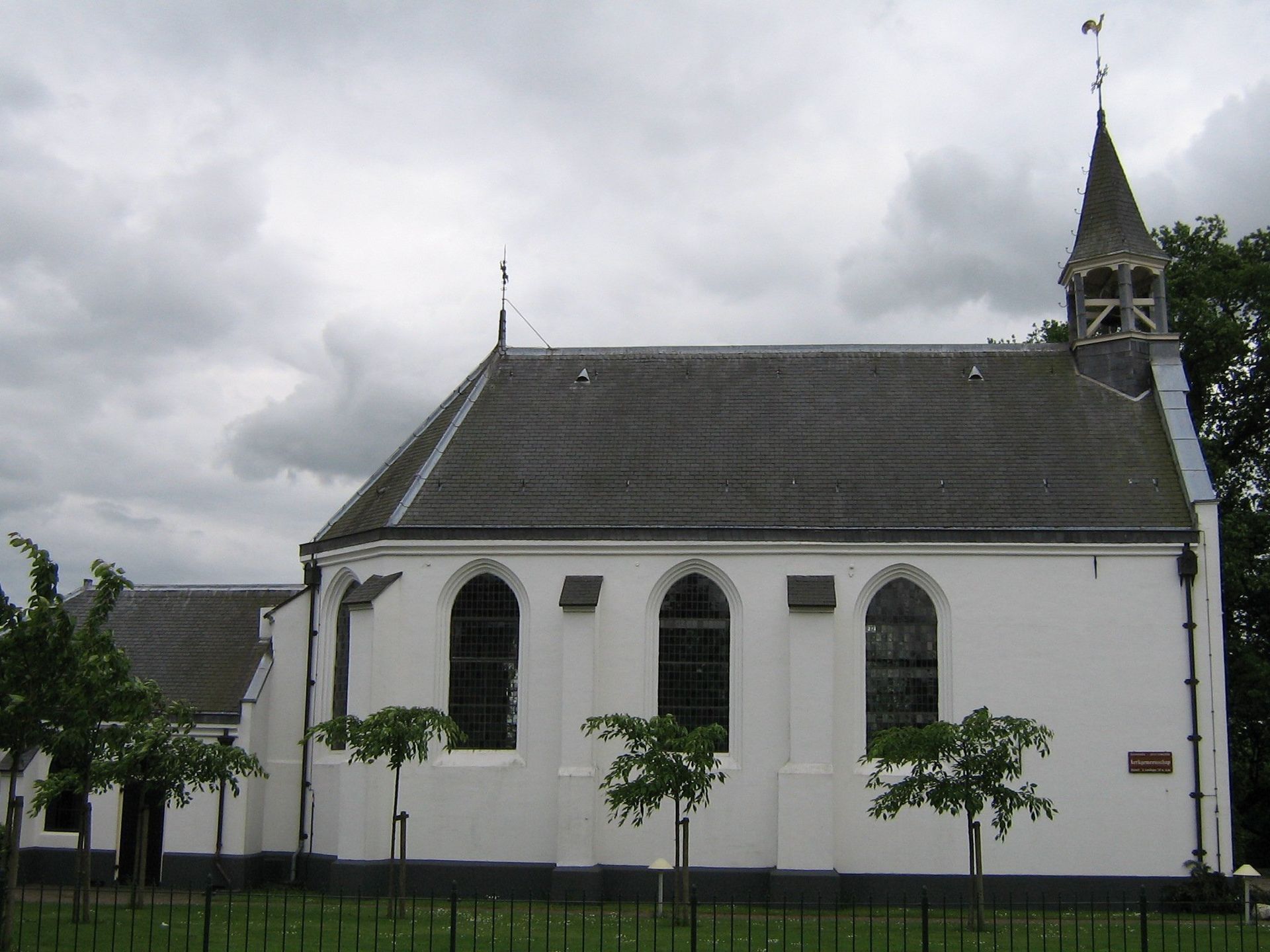 Een kleine witte kerk met een grijs dak