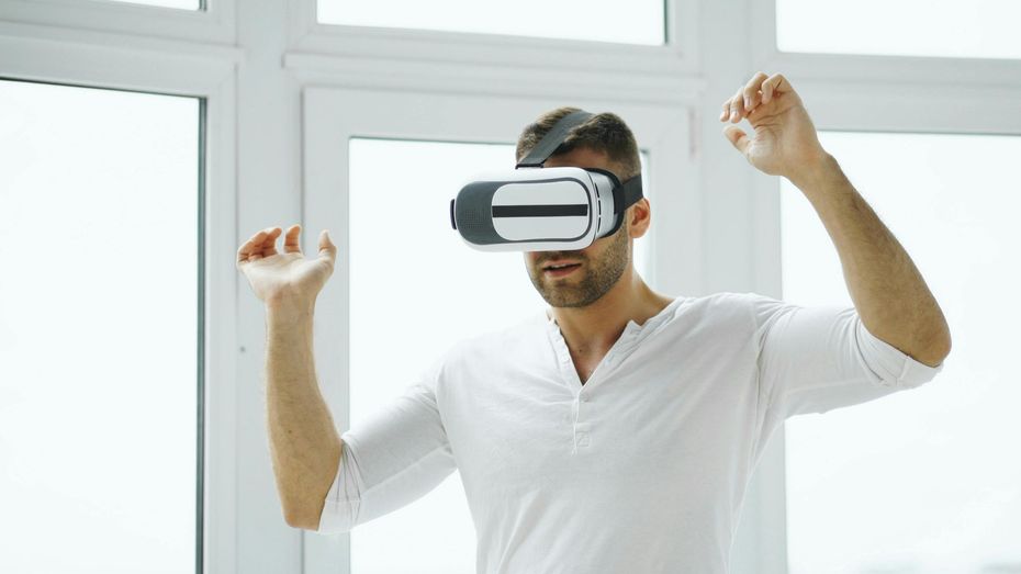 Person wearing VR headset, raising both fists in a bright room