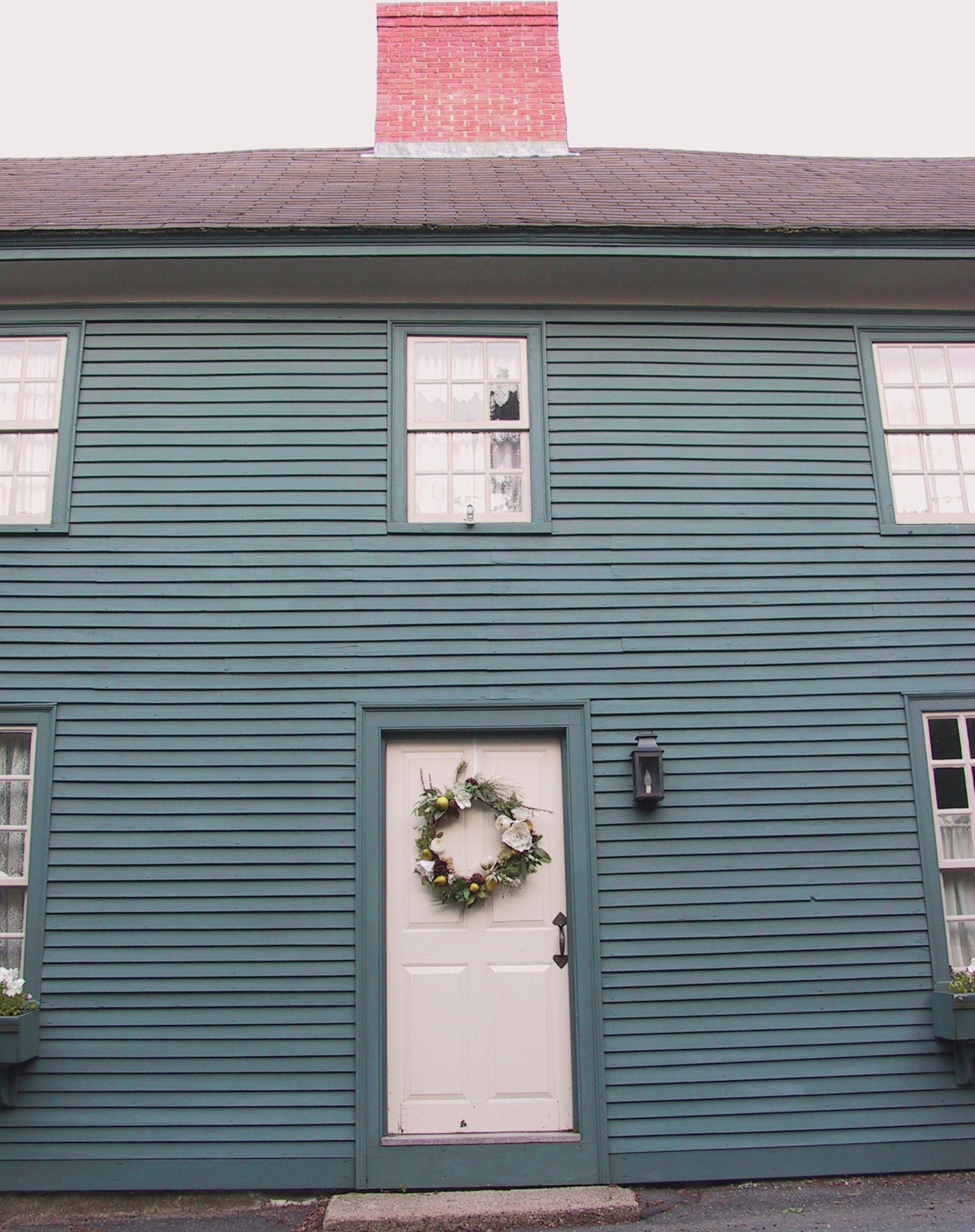 A green house with a white door and a wreath on it