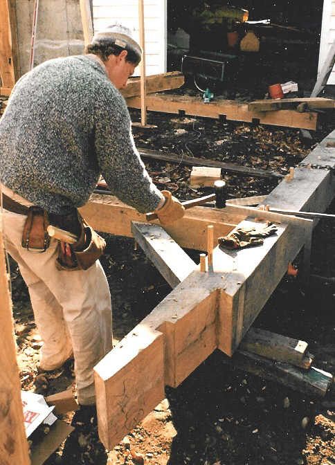A man is working on a wooden structure with a hammer