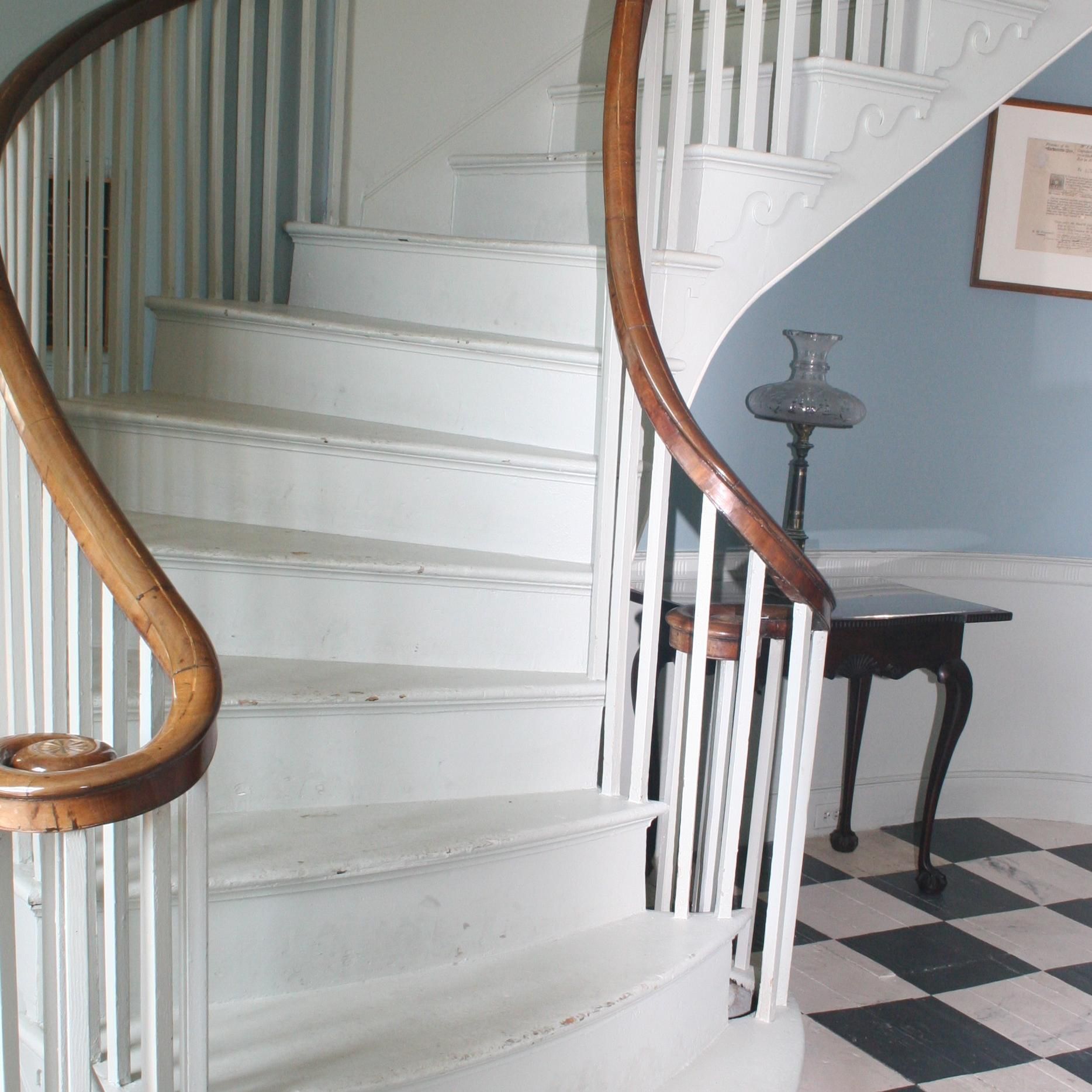 A spiral staircase with a wooden railing and a checkered floor