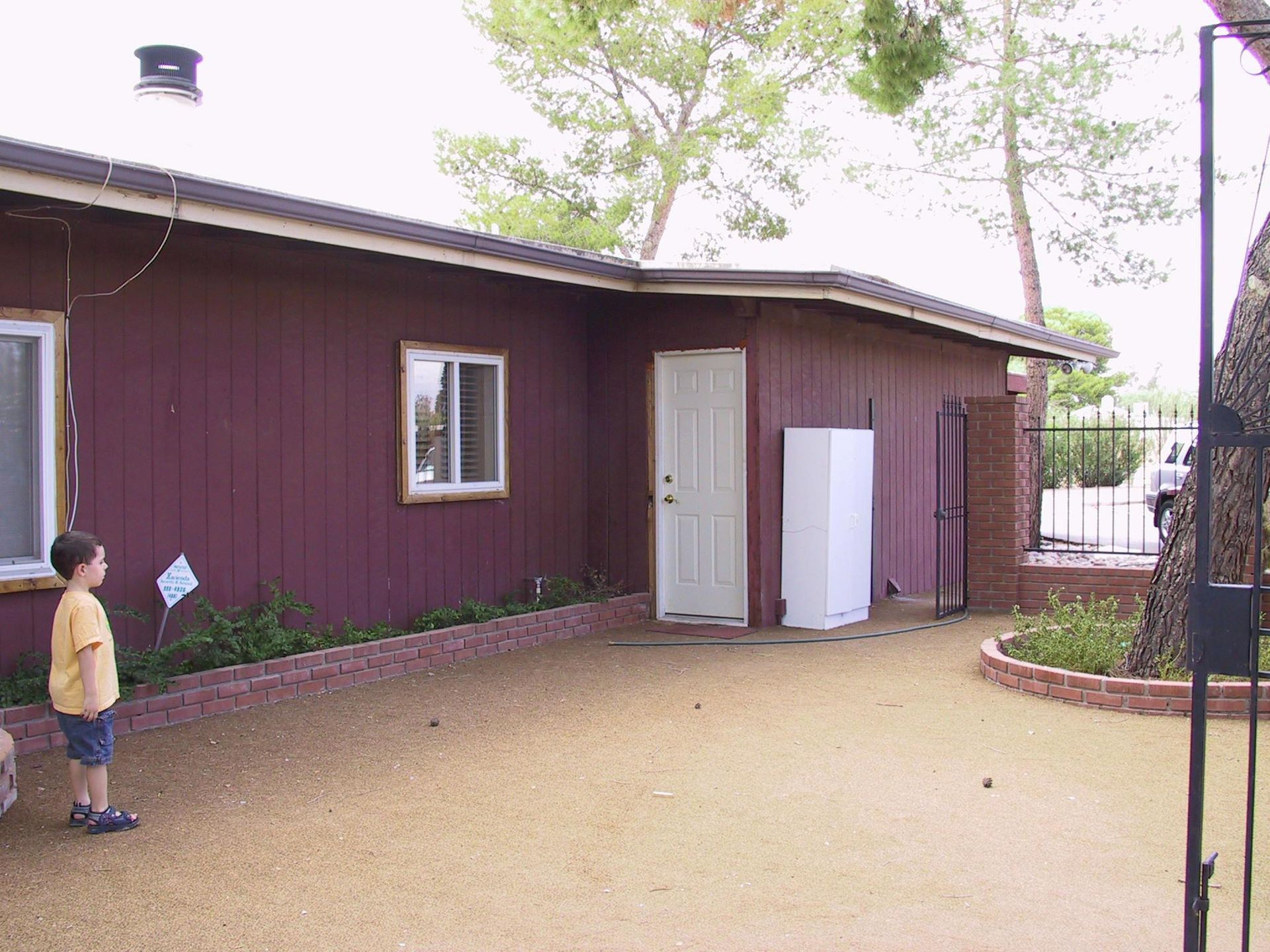 A boy is standing in front of a red house