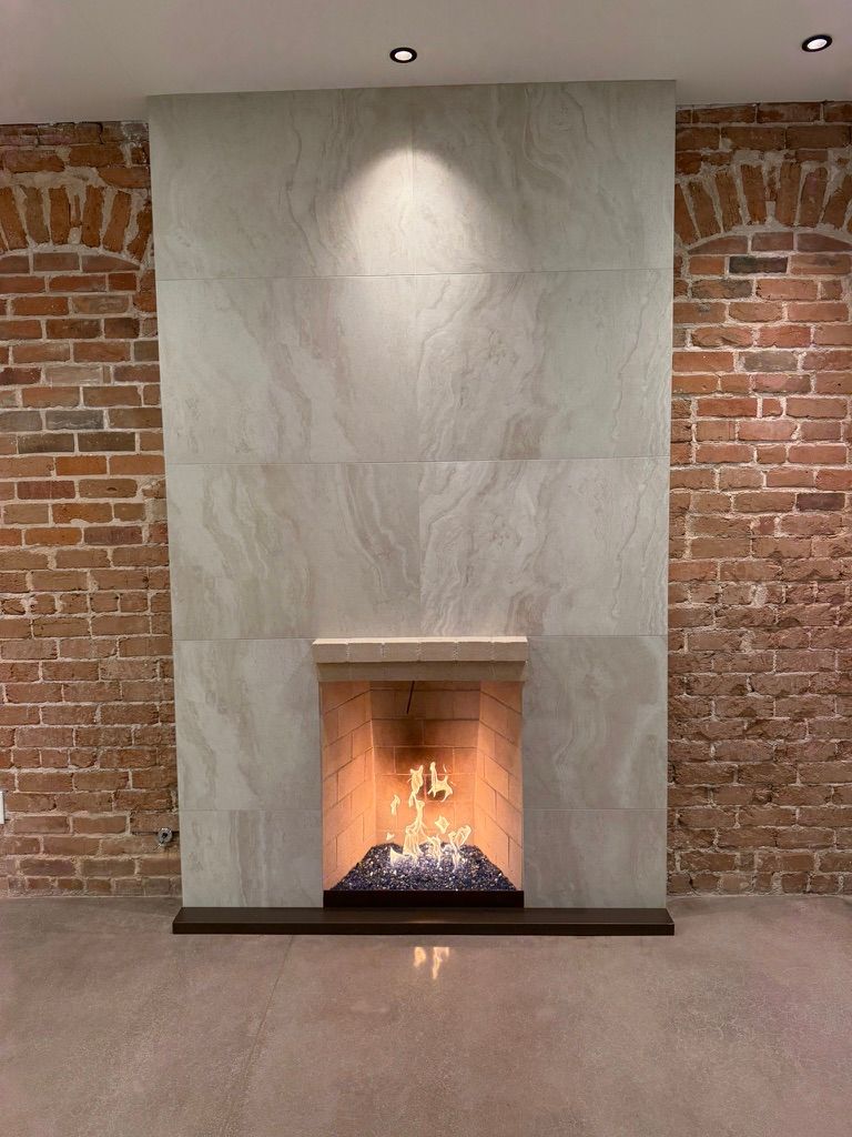 Modern fireplace in a minimalist room with exposed brick walls and a lit fire.