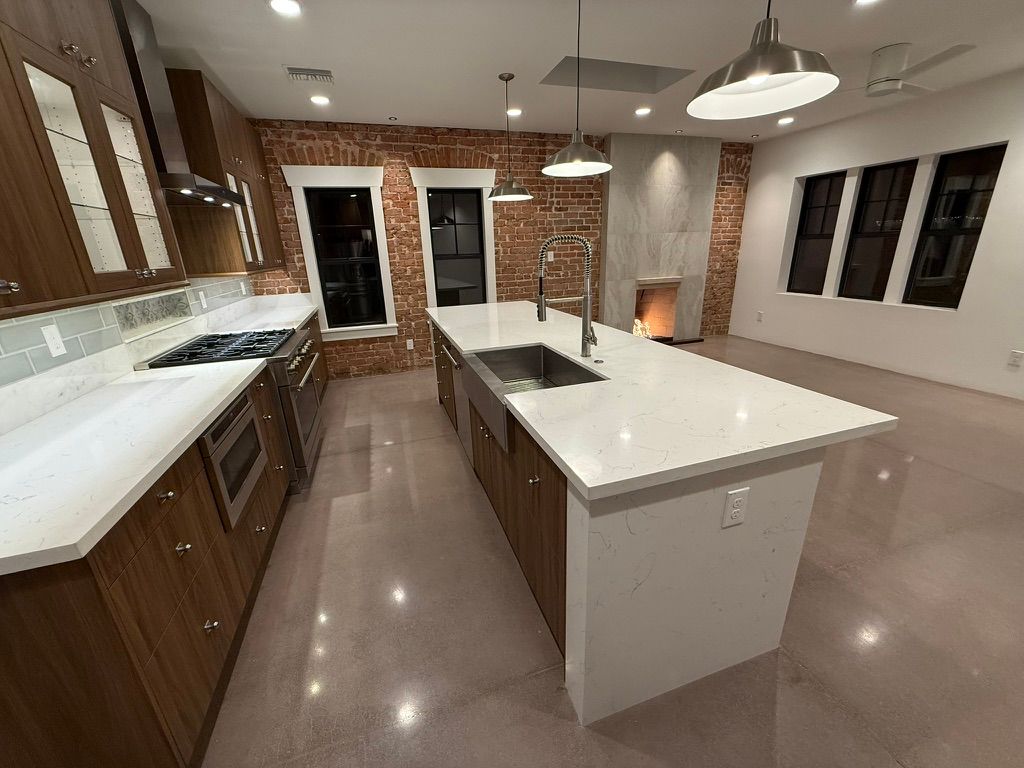 Spacious modern kitchen with wood cabinets, white island, brick backsplash, and pendant lights