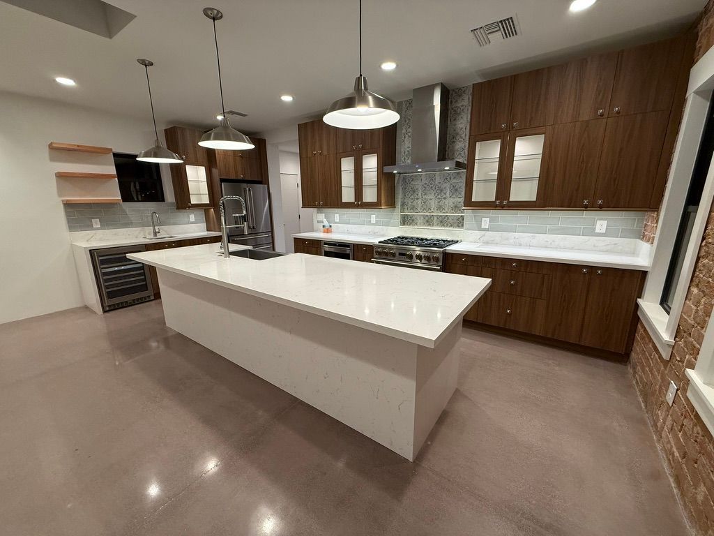 Modern kitchen with white island, wood cabinets, stainless appliances, and pendant lights
