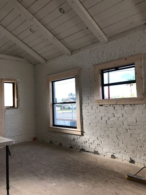 Interior room with white painted brick walls, exposed ceiling beams, and new windows.