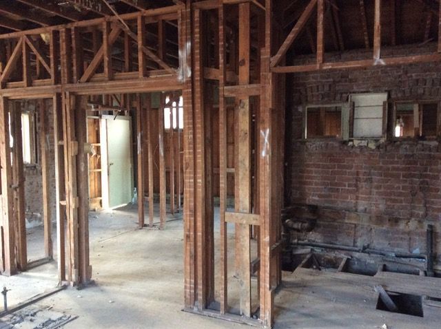 Interior of a building under renovation, showing exposed wooden framing and brick walls.
