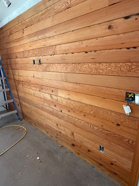 Wood-paneled wall with electrical outlets. Construction setting, wooden planks in horizontal rows.