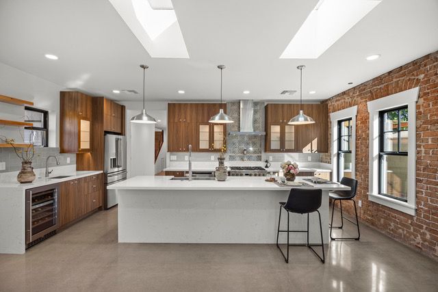 Modern kitchen with white island, wood cabinets, exposed brick wall, and skylights.