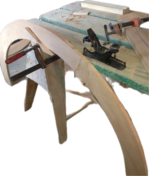 Woodworking with clamped curved wooden pieces on a workbench.
