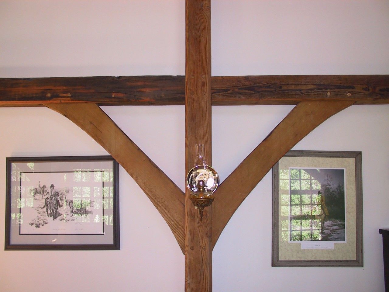 A picture of a man riding a horse is hanging on a wall next to a wooden beam.