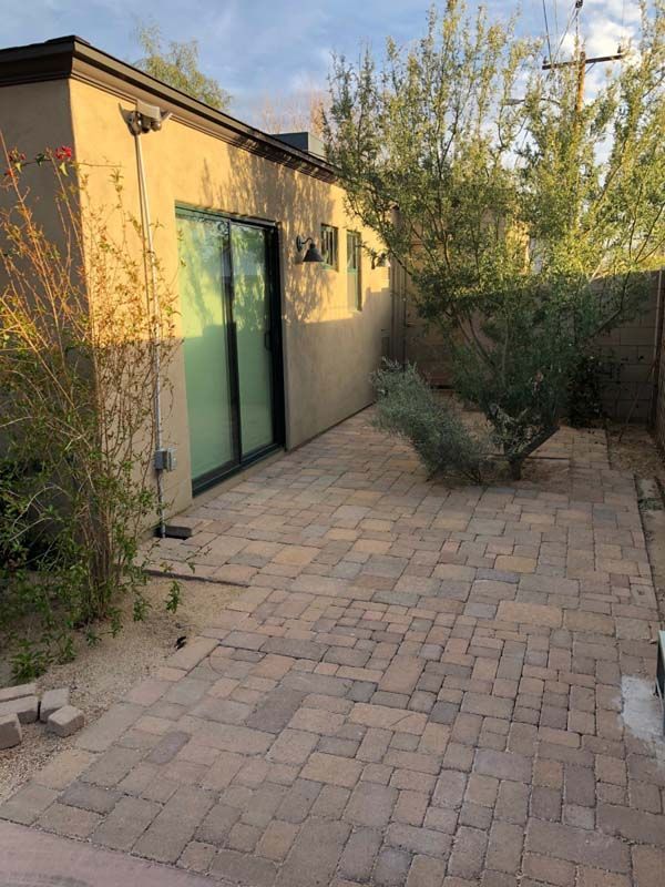 A brick patio in front of a house with a sliding glass door.