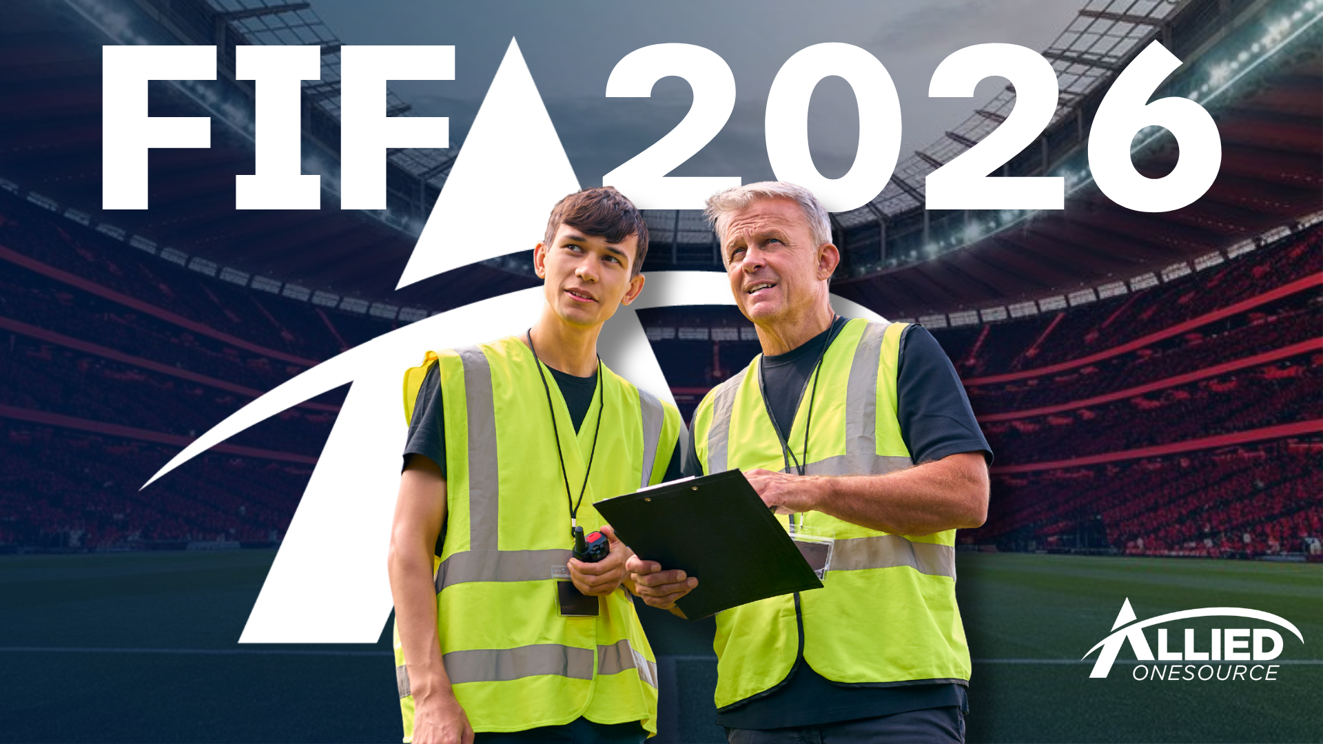 Two men in vests pose in front of a soccer stadium featuring the words 