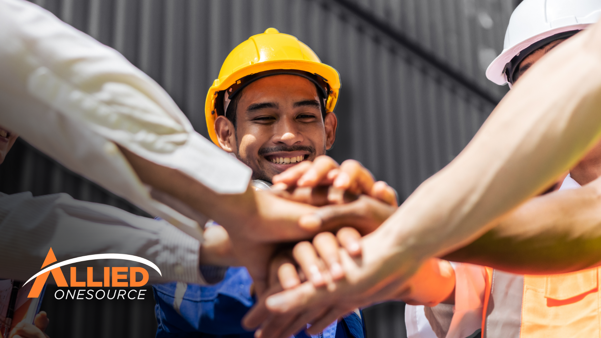 Construction workers in hard hats joining hands, representing employee engagement strategic action.