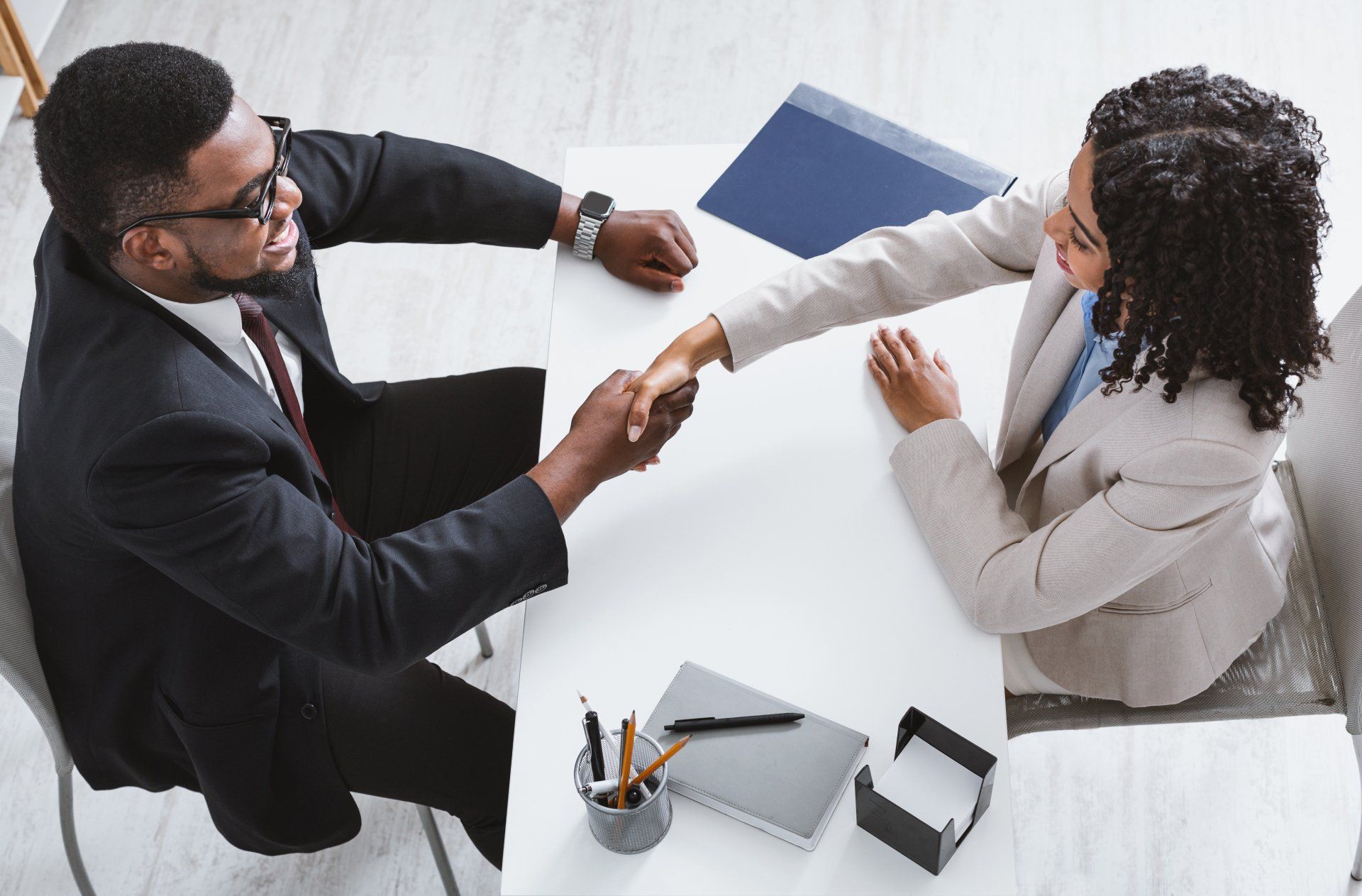 Above view of personnel manager shaking hands with vacancy applicant during job interview at office