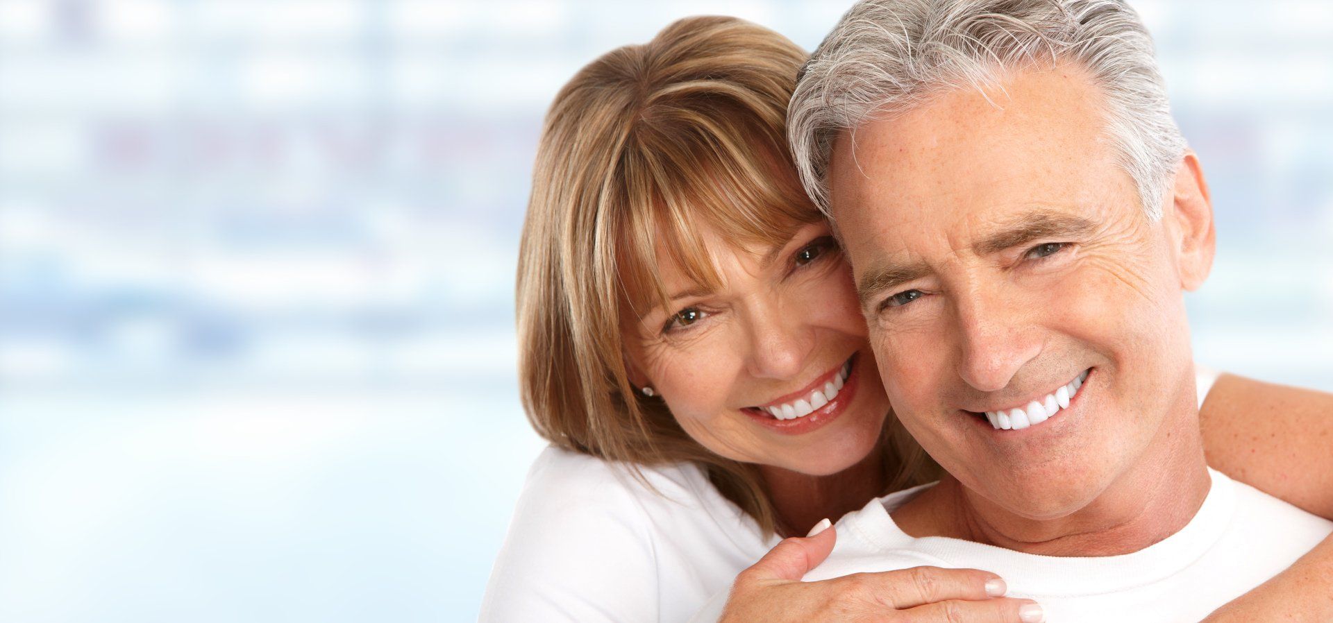 A man and a woman are hugging each other and smiling.